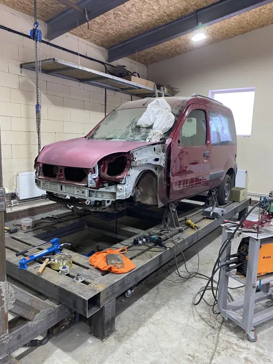Красный автомобиль на стапеле с разобранной передней частью
